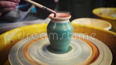 女陶工在陶工`车轮上画一个粘土花瓶。 手工陶器里面。